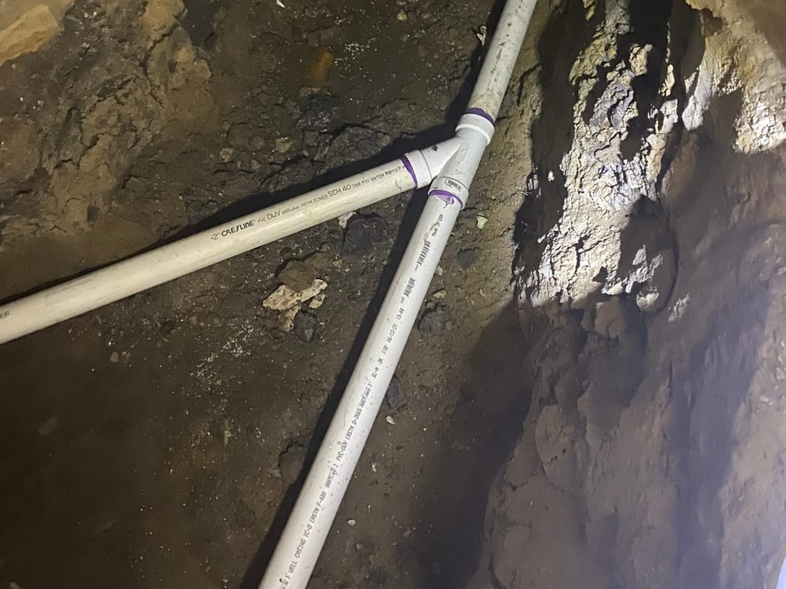 A hand-dug tunnel under a foundation with a new drain line by Encore Plumbing
